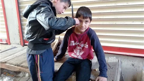 Cizre'de 13 yaşındaki berber, kapı önünde arkadaşlarını traş ediyor
