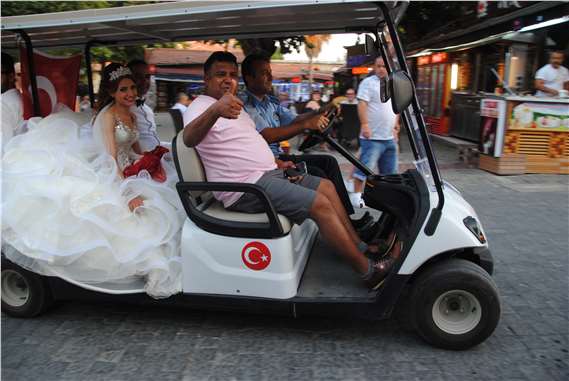 Yeni evlenen çiftler Side'de golf arabasıyla fotoğraf çektiriyor
